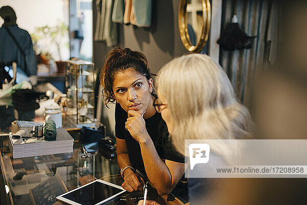Businesswoman discussing with female colleague in clothing store