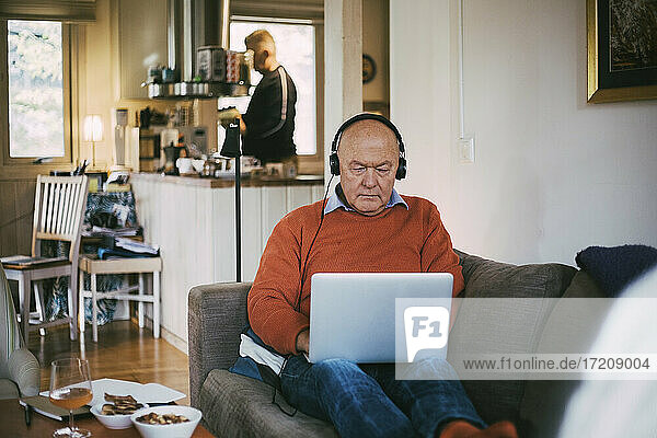 Älterer schwuler Mann  der einen Laptop benutzt  während er zu Hause sitzt