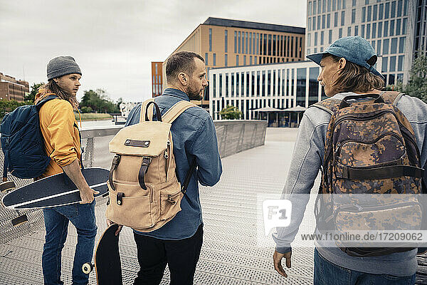 Male friends with backpack walking on bridge