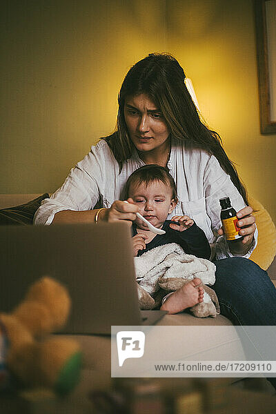 Mutter füttert Tochter im Wohnzimmer mit Medizin