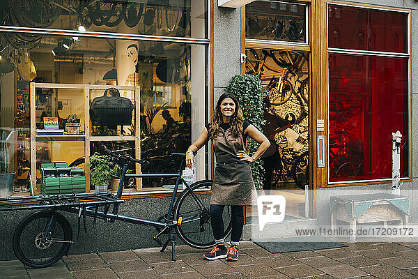 Lächelnde Besitzerin steht mit dem Fahrrad vor der Werkstatt