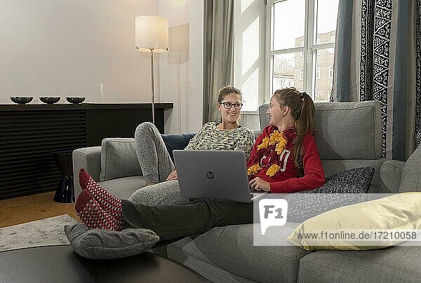 Two young woman sitting on a sofa with a laptop