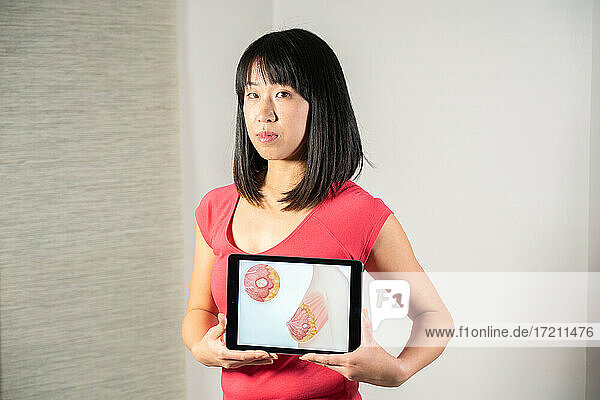 Frau hält Bildschirm mit Zeichnung von Brustkrebs