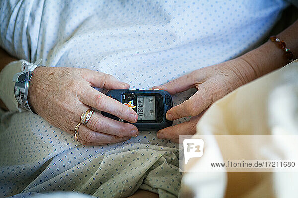 Patient adjusting the intensity of her implanted spinal cord stimulator to combat pain.
