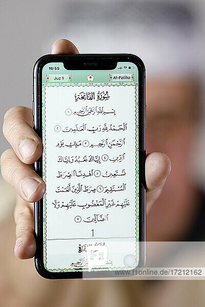 Mann zeigt einen elektronischen Koran auf einem Smartphone