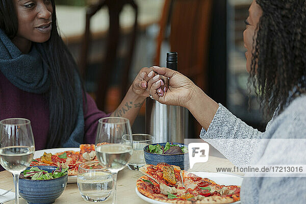 Mutter und Tochter halten Hände über Pizza und Salat Mittagessen