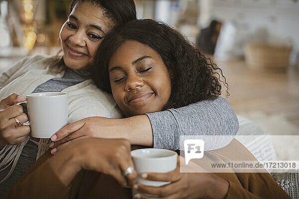 Zärtliche Mutter und Tochter kuscheln mit Tee