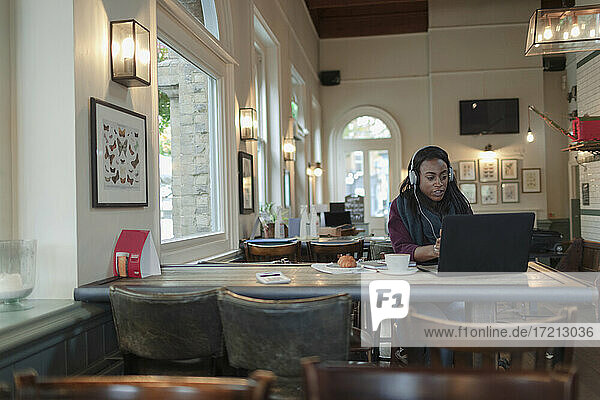 Geschäftsfrau mit Kopfhörer arbeiten am Laptop im Café