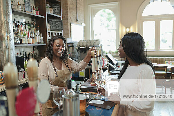 Bartender serving young woman in pub