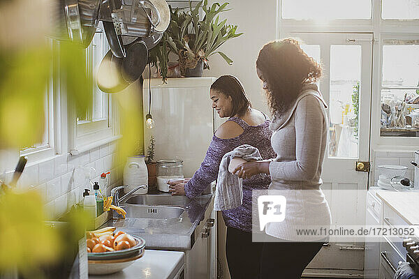 Mother and daughter doing dishes at kitchen sink