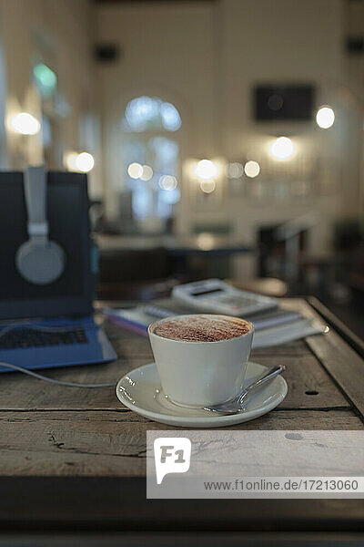 Cappuccino auf Cafe-Tisch neben Laptop