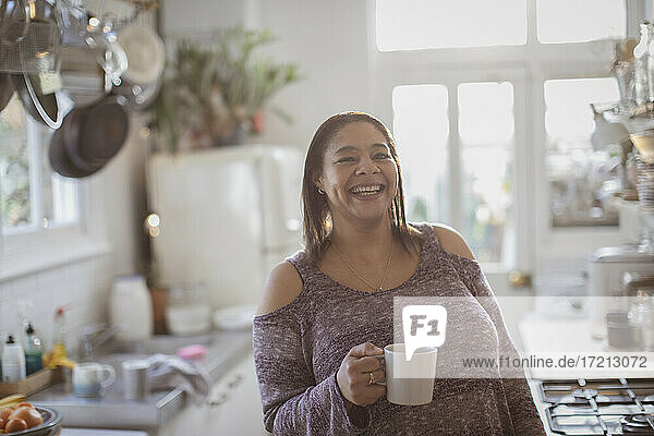Portrait happy woman drinking coffee in kitchen