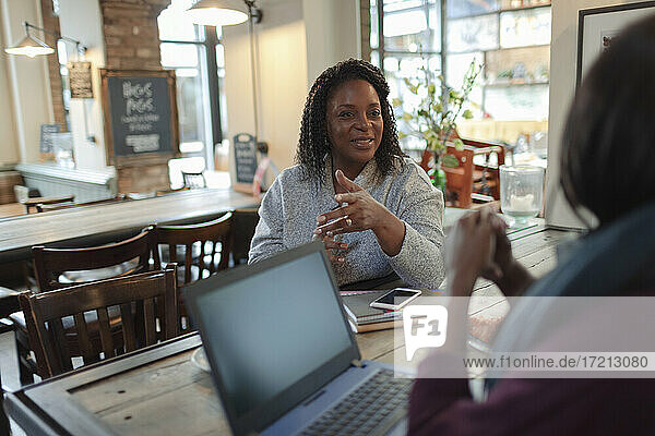 Businesswomen meeting and talking at laptop in cafe