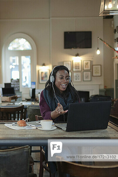 Geschäftsfrau mit Kopfhörer Videokonferenz am Laptop im Café