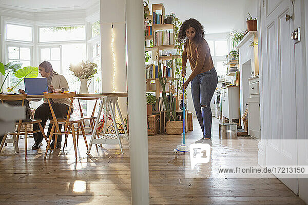 Frauen arbeiten und wischen Hartholzboden in der Wohnung