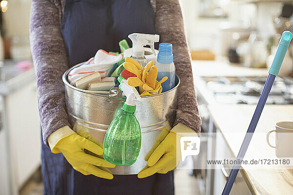 Frau hält Eimer mit Reinigungsmitteln in der Küche
