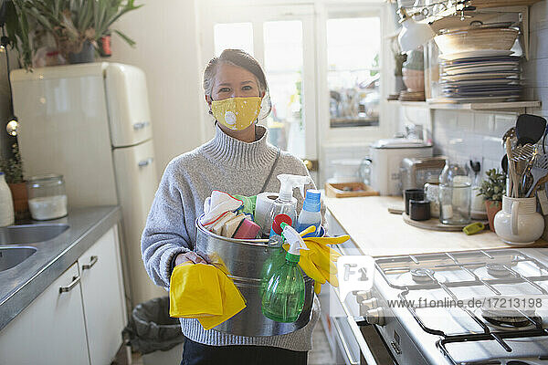 Porträt selbstbewusste Frau in Gesichtsmaske mit Küchenreinigungsmitteln