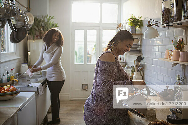 Mutter und Tochter tun Gerichte und machen Tee in der Küche