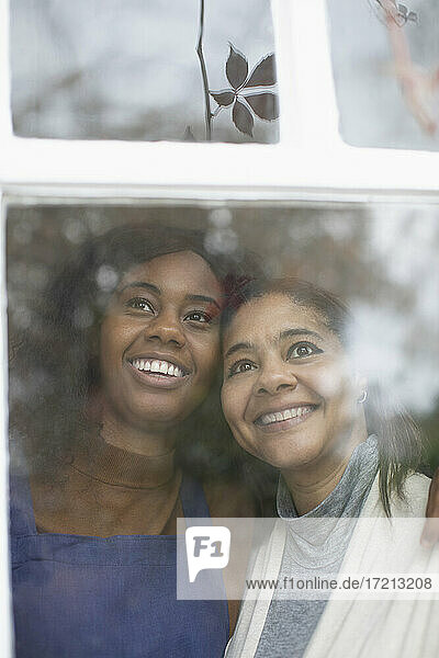 Glückliche Mutter und Tochter schauen aus dem Fenster