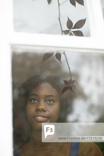 Nachdenkliche junge Frau schaut aus dem Fenster