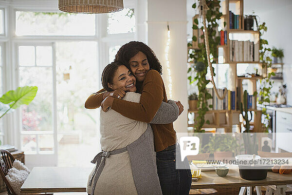 Happy mother and daughter hugging at home