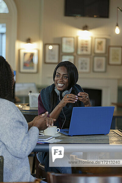 Glückliche Geschäftsfrauen reden und arbeiten am Laptop im Café
