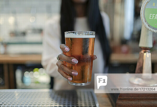 Close up female bartender serving pint of beer in pub