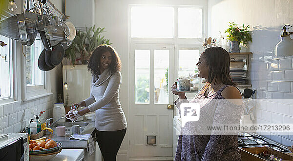 Mutter und Tochter tun Gerichte und genießen Tee in der Küche