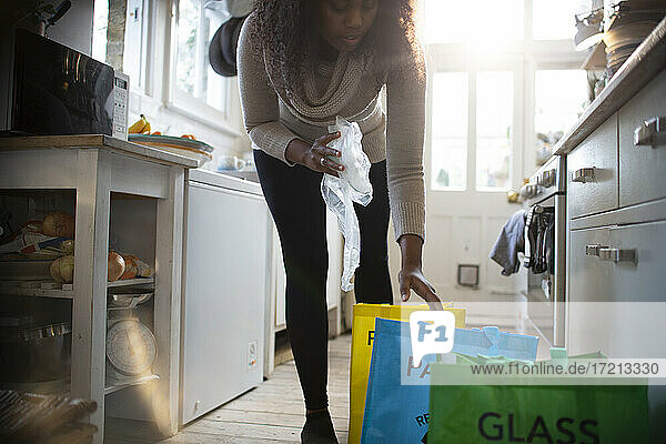 Frau sortiert Recycling in Säcke auf dem Küchenboden