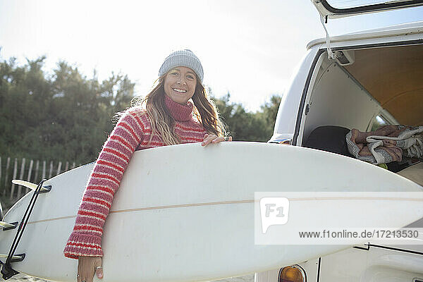 Porträt sorglos junge weibliche Surfer mit Surfbrett außerhalb van