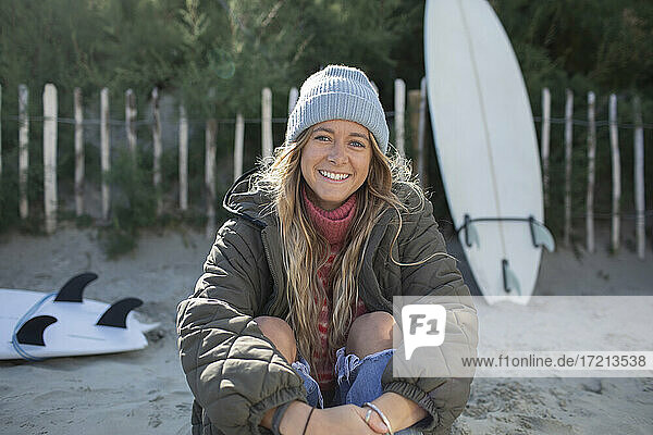 Porträt glücklich schöne junge weibliche Surfer sitzen am Strand