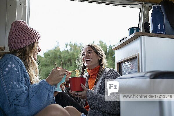 Glückliche junge Frauen Freunde essen Instant-Nudeln in Wohnmobil Van