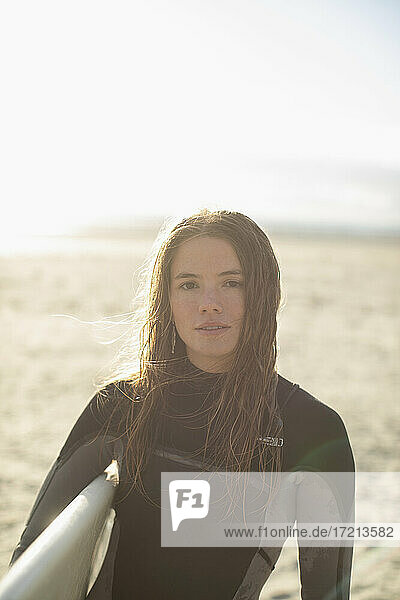 Porträt schöne junge weibliche Surferin mit nassen Haaren am sonnigen Strand