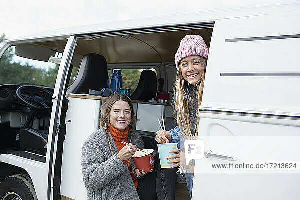 Porträt glücklich junge Frauen Freunde essen Instant-Nudeln in van
