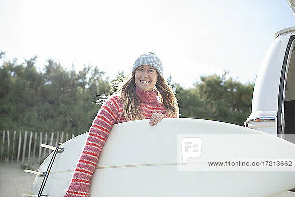 Porträt glücklich junge weibliche Surferin hält Surfbrett