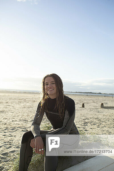 Portrait confident beautiful young female surfer in wet suit on beach