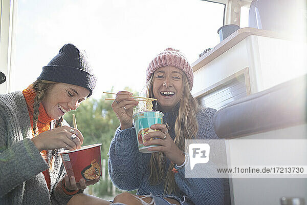 Porträt glückliche junge Frauen essen Instant-Nudeln in Wohnmobil Van