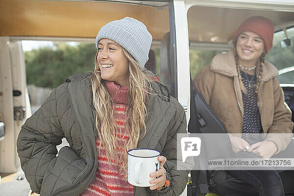 Glückliche junge Frauen Freunde trinken Tee an Camper van Türöffnung