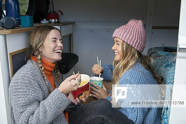 Glückliche junge Frauen Freunde essen Instant-Nudeln in Wohnmobil Van