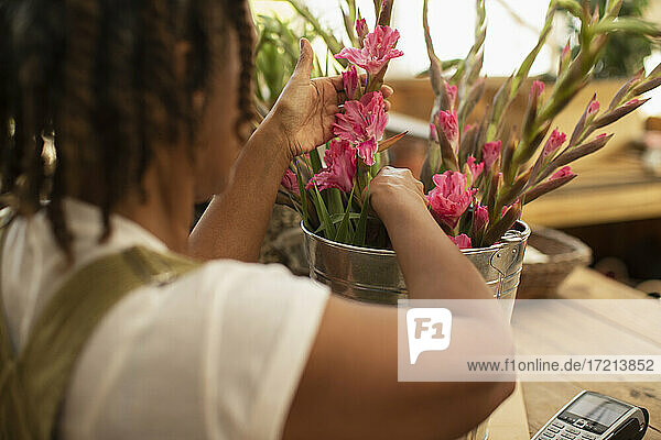 Weibliche Floristin arrangiert rosa Blumen in Eimer im Laden