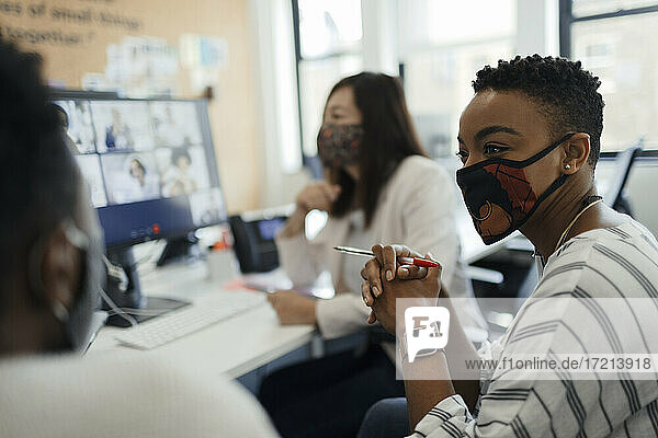 Business people in face masks video conferencing at office computer