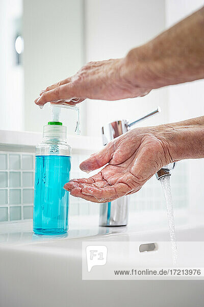 Ältere Frau beim Händewaschen mit Seife am Waschbecken im Bad