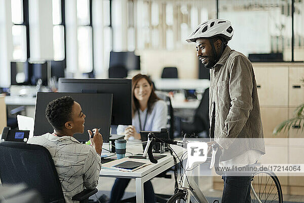 Geschäftsmann mit Fahrrad im Gespräch mit Geschäftsfrauen im Büro
