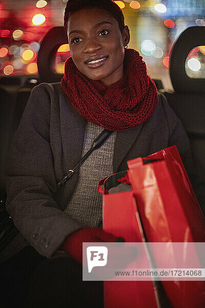 Junge Frau mit Weihnachtseinkaufstüten im Taxi