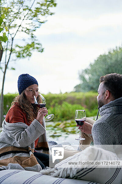 Paar trinkt Wein auf Terrassen-Kissen