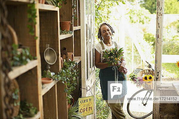 Porträt glückliche weibliche Blumenhändlerin mit Blumenstrauß in der Ladentür