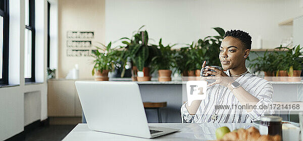 Junge Geschäftsfrau mit Kaffee arbeiten am Laptop im Büro
