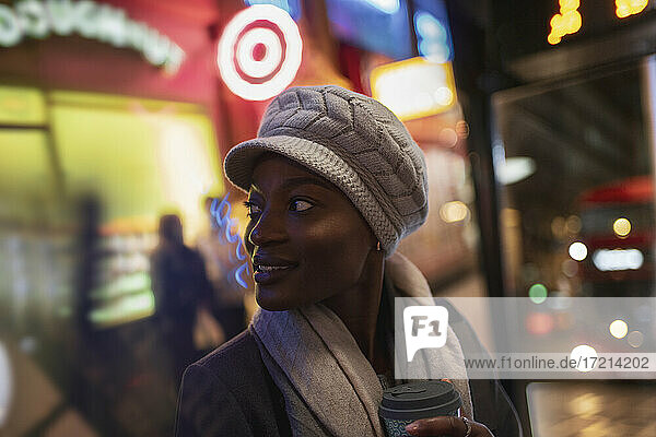 Junge Frau mit Hut auf dem Bürgersteig der Stadt bei Nacht