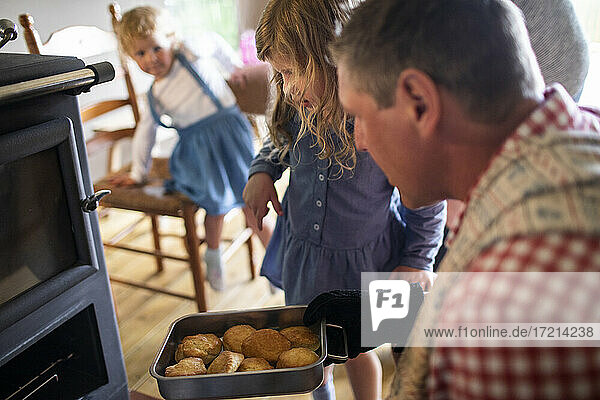 Vater und Tochter nehmen frische Kekse aus dem Ofen