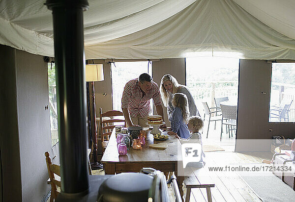 Happy family at dining table with strawberry cake on yurt tent